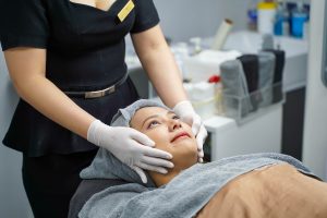 Closeup cosmetologists prepare customer's face before making facial massage with organic face scrub and smooth facial white mask cream